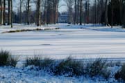 Blick über den verschneiten See zum Schloss im Queen-Auguste-Victoria-Park